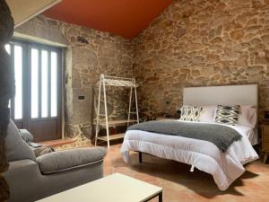 una camera da letto con un letto e un muro di pietra di Casa O Corvo, chalet cerca de Vigo en plena naturaleza a Vilacoba