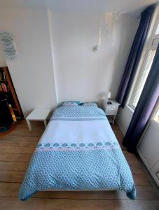 a bedroom with a bed with a blue and white comforter at Studio confort Verviers in Verviers