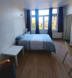 a bedroom with a bed and windows and a wooden floor at Studio confort Verviers in Verviers