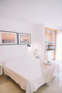 a white bedroom with a white bed and two windows at Apartamento Añoreta Malaga 318 in Torre de Benagalbón