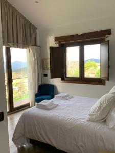 una camera con letto, sedia blu e finestre di Casa O Corvo, chalet cerca de Vigo en plena naturaleza a Vilacoba