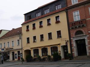 a building on a street next to a brick building at Hermanns Hotel Zum Goldenen Stern in Jüterbog