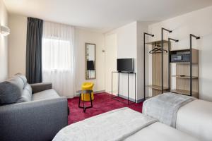 a living room with a couch and a tv at Sure Hotel by Best Western Les Portes de Montauban in Montauban