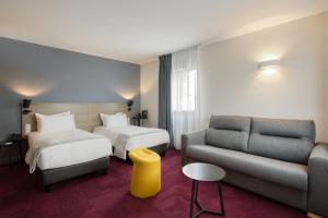 une chambre d'hôtel avec deux lits et un canapé dans l'établissement Sure Hotel by Best Western Les Portes de Montauban, à Montauban