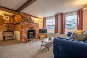 a living room with a brick fireplace and a blue couch at The Town House in Woodbridge