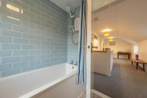 a bathroom with a tub and blue tiles on the wall at The Town House in Woodbridge