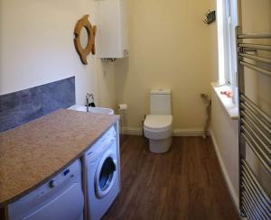 uma casa de banho com uma máquina de lavar roupa e um WC em Owlswood Apartments em Edinbain