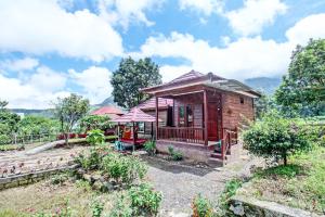 a small wooden house with a porch in a field at OYO 92142 Ujung Samalas Homestay in Labuan Lombok