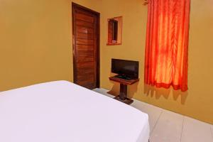 OYO 92142 Ujung Samalas Homestay في لومبوك: غرفة نوم بسرير وتلفزيون على طاولة