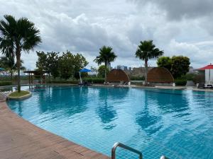 a large blue swimming pool with palm trees in the background at Almas Suite in Nusajaya