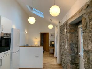 a kitchen with white appliances and a stone wall at Arch Cottage @ The Old Vicarage in Pendeen