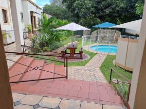 a patio with a table and umbrella next to a pool at Amigos Bed & Breakfast - No loadshedding in Nelspruit