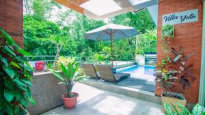 un patio con sombrilla, sillas y piscina en Villa Dewata with Chill Spot Private Pool and Karaoke, en Batu