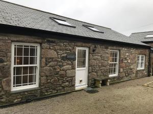 a stone building with a white door and windows at Arch Cottage @ The Old Vicarage in Pendeen