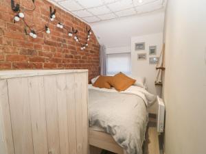 a bedroom with a bed and a brick wall at 1 Dinas cottages in Caernarfon