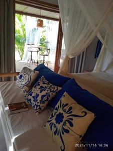Schlafzimmer mit einem Bett mit blauen und weißen Kissen in der Unterkunft Casa Paula in Barra Grande
