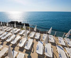 a group of chairs and umbrellas on the beach at FELLINI SUITES Lungomare near the sea in Catania