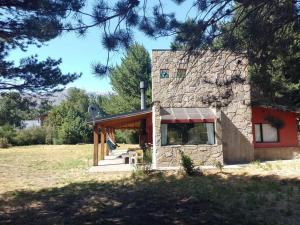 uma casa de pedra com uma porta vermelha e escadas em Cabaña Quela em San Martín de los Andes