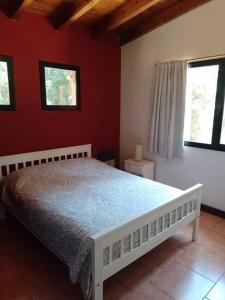 - une chambre avec un lit blanc dans un mur rouge dans l'établissement Cabaña Quela, à San Martín de los Andes