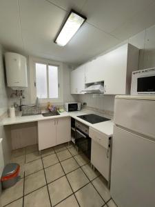 a kitchen with white cabinets and a white refrigerator at Habitación cómoda en Barcelona in Esplugues de Llobregat