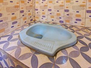 a toilet in a bathroom with a tiled floor at OYO 92149 Ashooy Homestay in Lombok