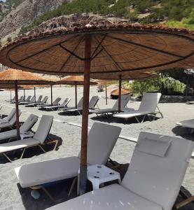 grupa krzeseł i parasol na plaży w obiekcie Agia Roumeli Hotel w mieście Ajia Rumeli