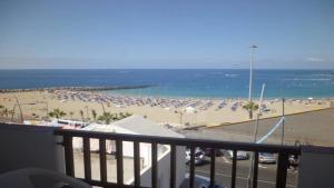 einen Balkon mit Blick auf einen Strand mit Sonnenschirmen in der Unterkunft Virginia Apartment in Los Cristianos