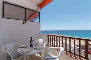 einen Tisch und Stühle auf einem Balkon mit Strandblick in der Unterkunft Virginia Apartment in Los Cristianos