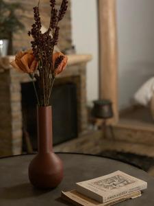 un jarrón con flores en una mesa junto a un libro en Νύμφες Σαλέ Ιαίρα, 