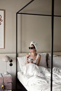 a woman sitting in bed with a bowl of food at MÜHLENHOF ROOMS boutique bed & breakfast in Langenlois