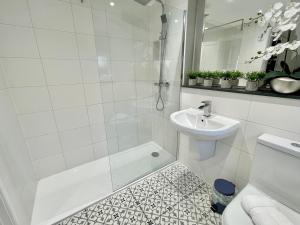 a white bathroom with a shower and a sink at The Balmoral close to the racecourse in York