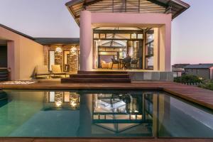 Pezula Sunset Views في كنيسنا: منزل به حوض سباحة أمام المنزل