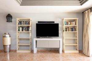 sala de estar con TV y estanterías de libros en Villa lussuosa a 1,5 chilometri da Costa Adeje, en Adeje