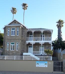 an old stone house with palm trees in the background at Twin Palms Accommodations in Mossel Bay