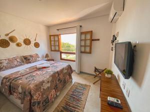 a bedroom with a bed and a flat screen tv at Maruê Guesthouse Porto de Pedras in Pôrto de Pedras