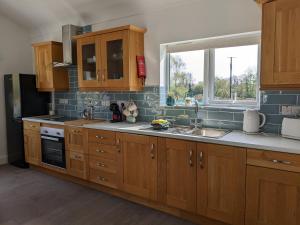 a kitchen with wooden cabinets and a sink and a window at Willow Lodge in Lisnaskea
