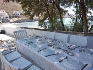 a white table with plates and silverware on it at VILLA KANTOUNI ON THE BEACH in Panormos Kalymnos