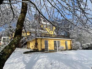 a yellow house with snow in front of it at Wollmeiner's Lodge in Arnsberg