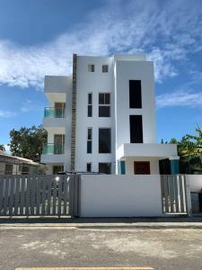 un bâtiment blanc avec une clôture devant lui dans l'établissement Hermoso Apartamento en Santiago, à Santiago de los Caballeros