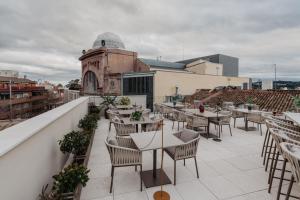 ein Dachrestaurant mit Tischen und Stühlen auf dem Dach in der Unterkunft Hotel Petit Luxe in Terrassa