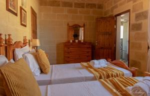 a bedroom with two beds and a dresser at Tan-Nanna Holiday Home in Xagħra
