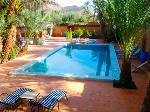 a swimming pool with two chairs and a table at Chez Ali in Zagora