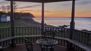 a table and chairs on a porch with a view of the ocean at Amherst Shore Country Inn in Lorneville