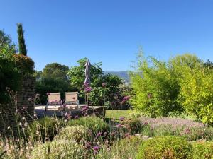 a garden with two chairs and flowers at Villa Cabrida in Cabrières-dʼAvignon