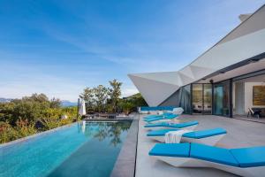 an infinity pool with blue lounge chairs next to a house at Luxury Villa Korcula Diamond in Žrnovo