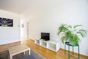 sala de estar con TV y maceta en Donaufeld Living - Modernes und helles Apartment, en Viena