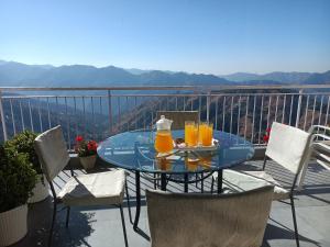 a glass table with orange juice on top of a balcony at Hostie Dale View North-3BHK, near Naldehra Golf course in Mashobra