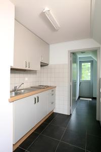 a kitchen with white cabinets and a black tile floor at Pivoné Assebroek in Bruges