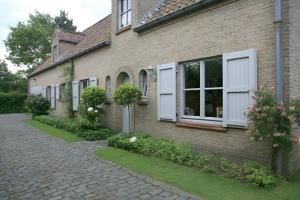 a brick house with white windows and a brick driveway at Pivoné Assebroek in Bruges