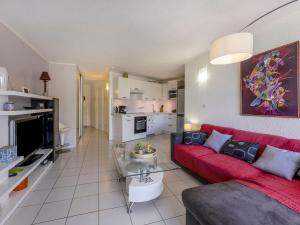 a living room with a red couch and a kitchen at Apartment Les Goélands-1 by Interhome in Cap d'Agde